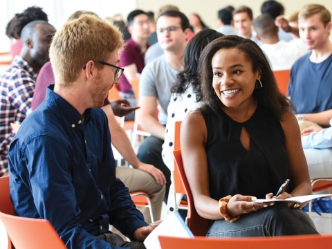 Students at orientation in orange chairs