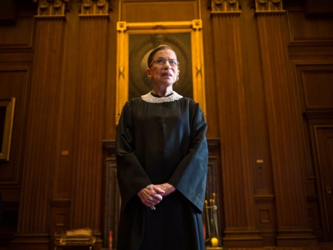 Ruth Bader Ginsburg wearing her justice robes in front of a portrait