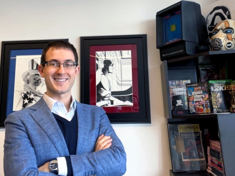 Joshua Simmons in glasses and blue blazer next to bookshelf with memorabilia from his court cases