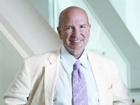 Balding man in white jacket and lavender tie 