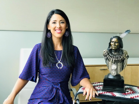 Woman in purple dress next to bust of Native American leader