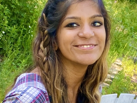 Image of a woman smiling and wearing a multi-colored shirt