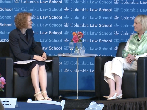 Two women sitting in armchairs in front of a Columbia Law School backdrop
