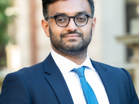 Professor Ashraf Ahmed smiling. He wears glasses with a blue suit and necktie.