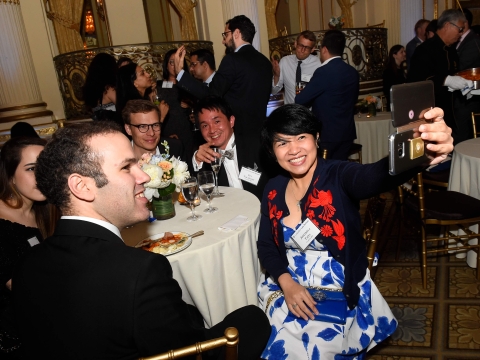 Alumni seated at a table at the 2018 Reunion kickoff pose for a selfie