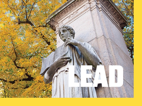 The word LEAD superimposed over a picture of a statue holding a book at the university gates