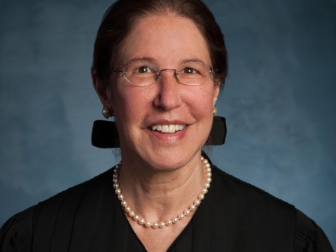 Dark-haired woman in judge's robe and pearls