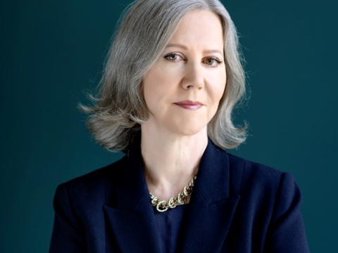 Portrait shot of a woman with gray hair in a black jacket and silver necklace