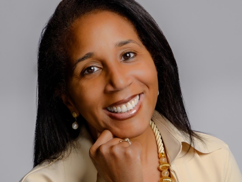 Karyn Temple in beige jacket resting her chin on her hand