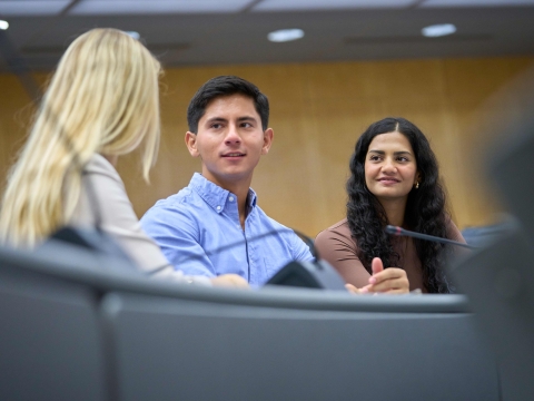 Three students sitting together in a lecture hall.
