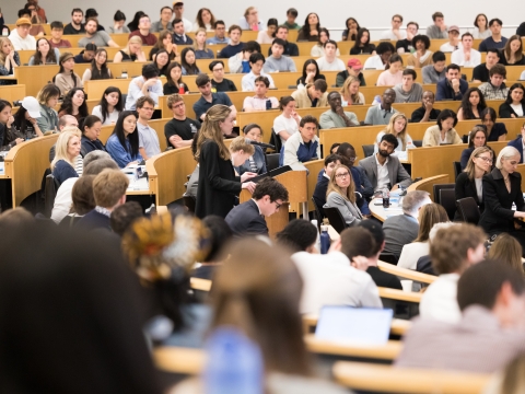 A student at the podium surrounded by fellow students, faculty, and family watching the 2026 Harlan Fiske Stone Moot Court finals.