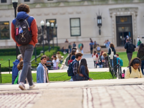 Students walk on campus in front of Butler Library.