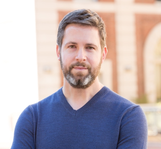 Portrait of Professor David Pozen, who is standing in front of a brick wall and smiling.