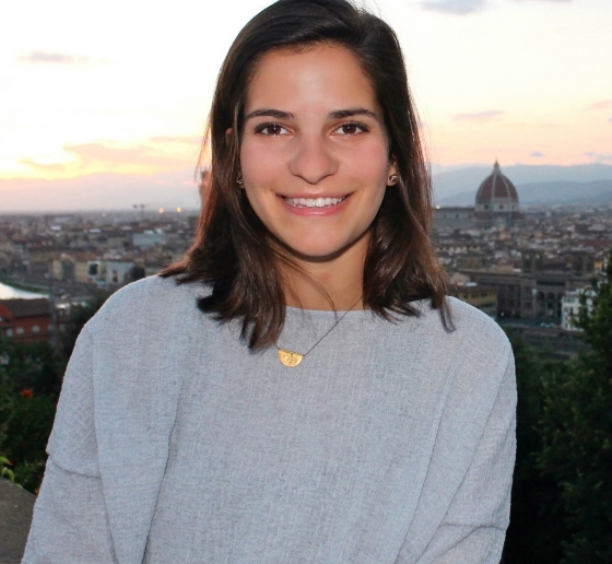 Columbia Law School graduate Emma DiNapoli ’20 in a pale gray sweater with clouds behind her