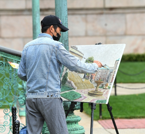 Man in a cap painting outdoors