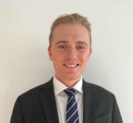 Male student in a suit and blue tie, smiling