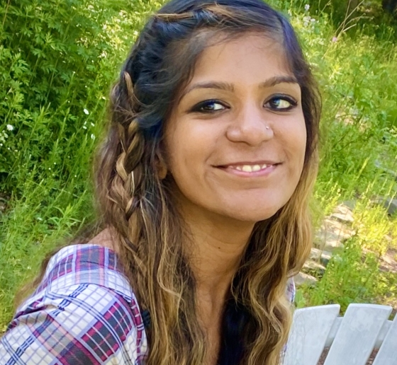 Image of a woman smiling and wearing a multi-colored shirt