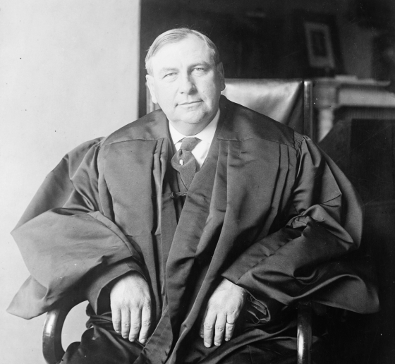 Black and white photo of a man seated wearing justice's robes