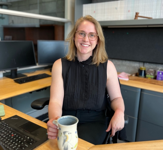 Blonde woman with glasses at desk with coffee mug