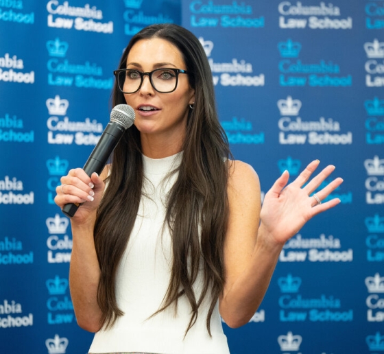 Michelle Hyncik in glasses and white blouse holding a microphone