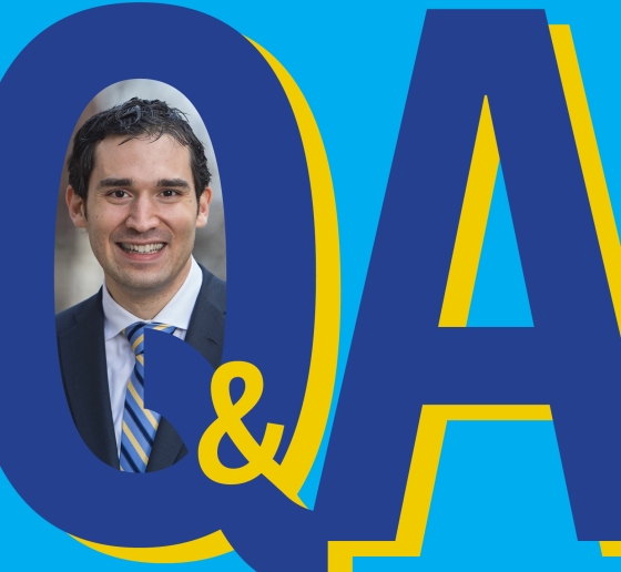 Letters Q & A in blue with photo of a dark haired man in jacket and tie