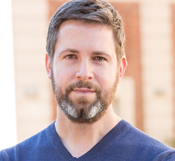 Portrait of Professor David Pozen, who is standing in front of a brick wall and smiling.