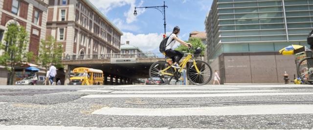 A student rides a yellow bicycle in front of the Law School.