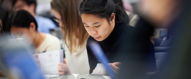 A student flips the page of a book in a lecture.