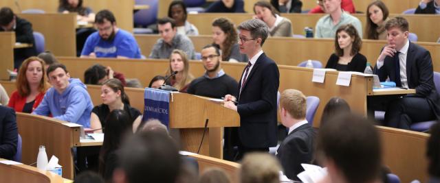A student stands at a podium in a lecture hall.