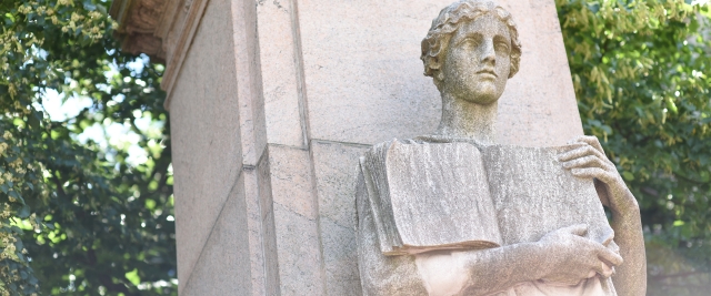 A statue holding a book outside the Broadway gates to Columbia's campus