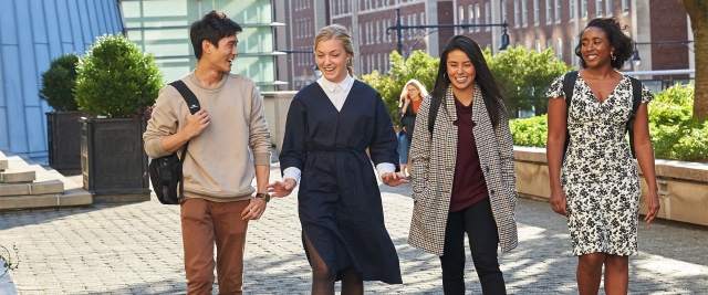 Four students walk on Revson Plaza.