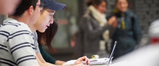 Students work on laptops in the lobby of Jerome Greene Hall.