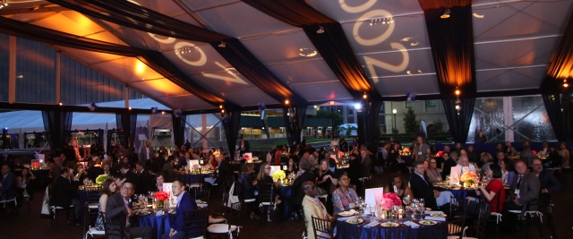 Alumni gather under a tent illuminated with projections of the years 2002 and 2007