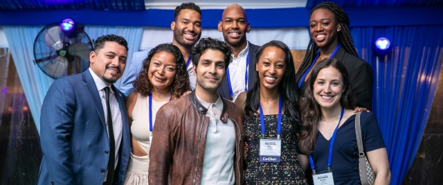 Eight Alumni stand in a group smiling at Reunion 2025