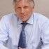 President Lee Bollinger smiles while folding his hands on a desk in front of him.