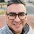 Pictured above is Professor Rodriguez. He has almond shaped brown eyes, tan skin, and straight hair that is combed over to the side. He is wearing glasses and a light grey L.L.Bean quarter zip. 