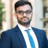 Professor Ashraf Ahmed smiling. He wears glasses with a blue suit and necktie.