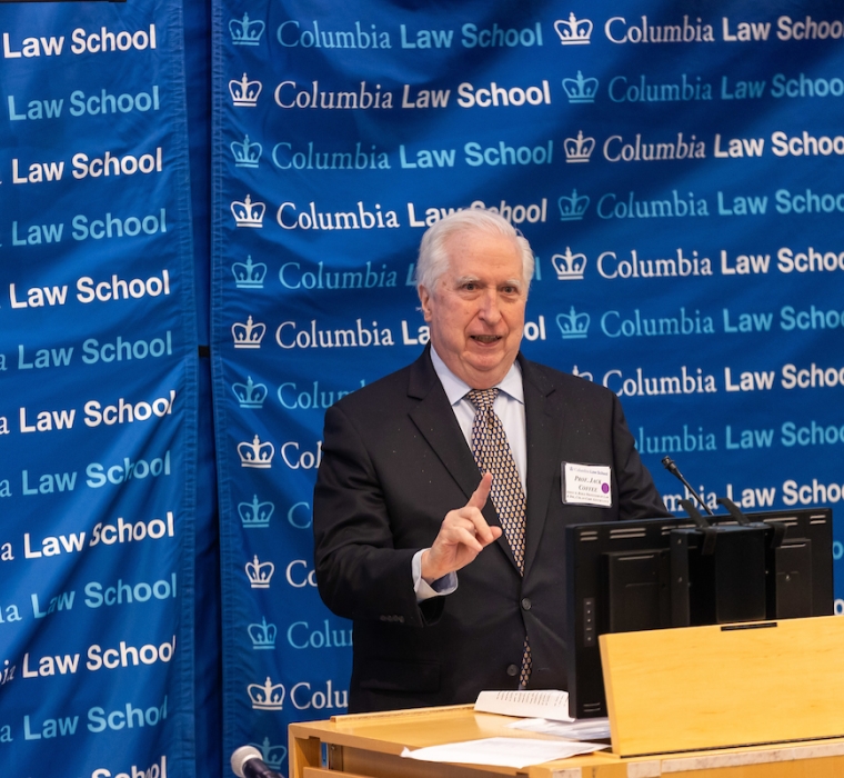 Man in tie at podium in front of Columbia Law School banner