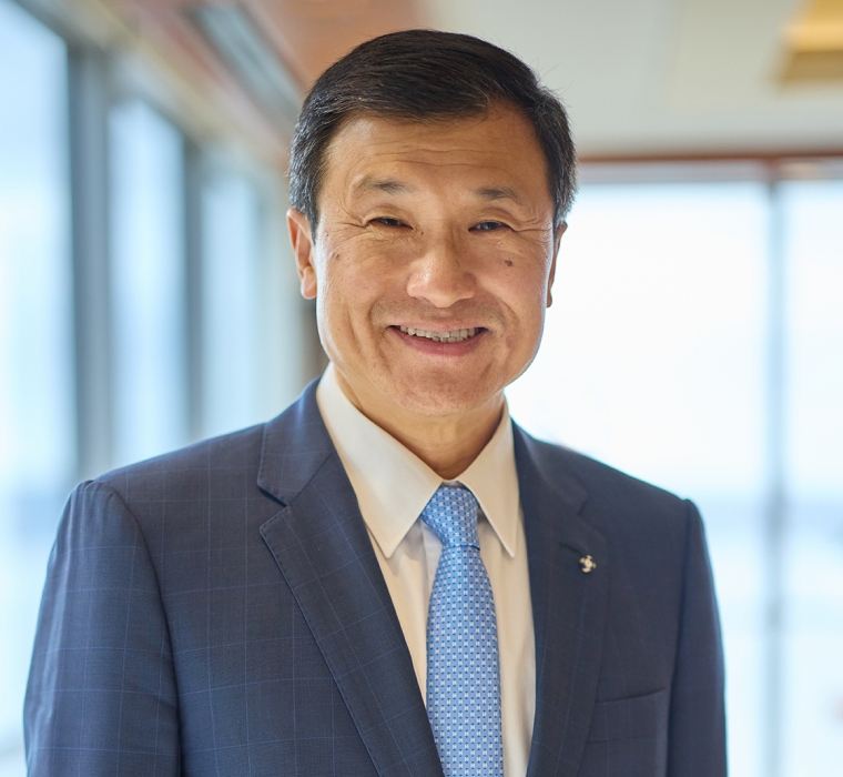 Headshot of a man wearing a blue jacket, white shirt, and blue tie