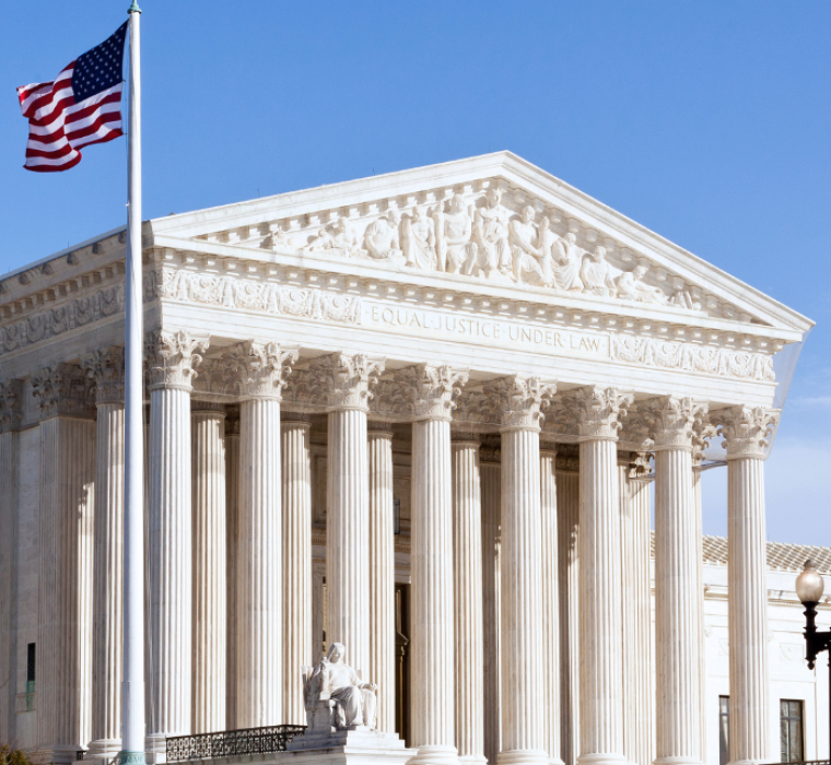 The exterior of the Supreme Court Building. An American flag waves in the air to the right of the building.
