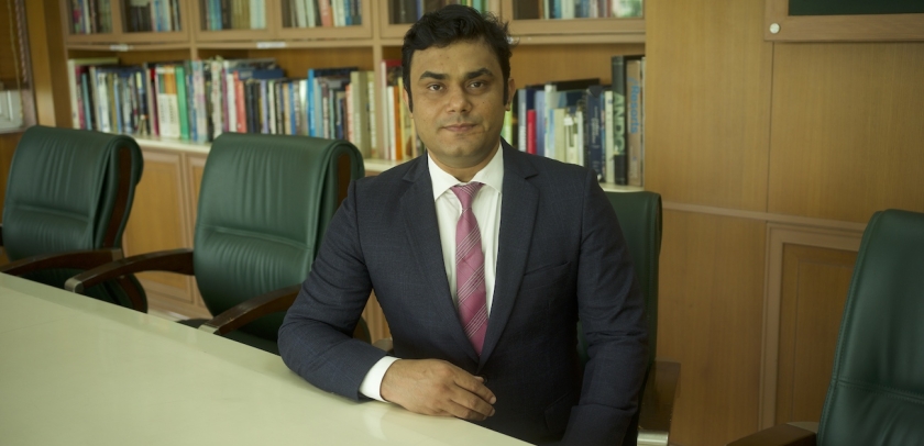 Bhagwati Fellow Devranjan Mishra in suit and tie sitting at conference table