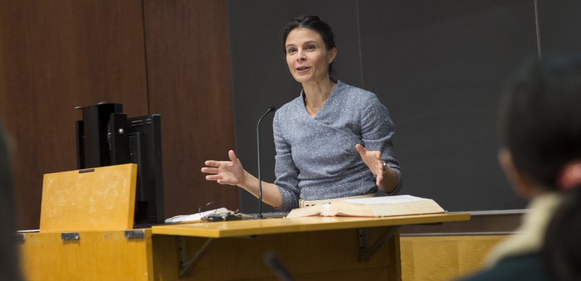  Professor Maeve Glass stands behind a lectern in a classroom at Columbia Law School/