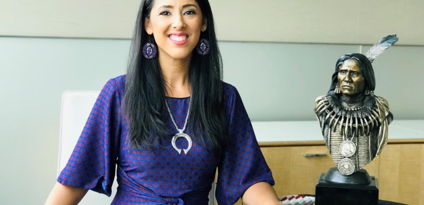 Woman in purple dress next to bust of Native American leader