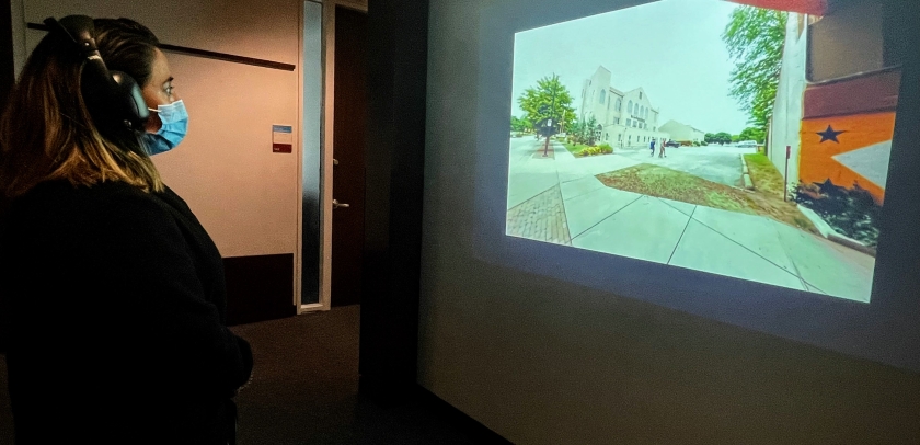 A woman wearing headphones looking at an image on a wall