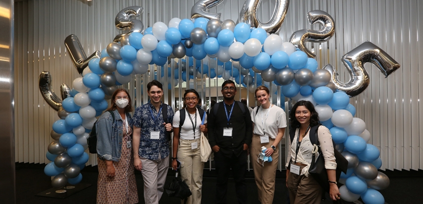 Six members of the class of 2025 pose in front of blue and white balloon arch with additional silver balloons that spell out CLS 2025.