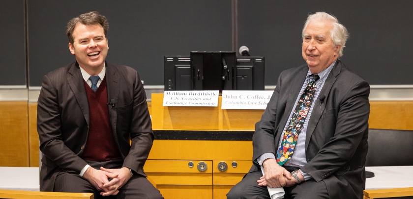 Two men seated, smiling 