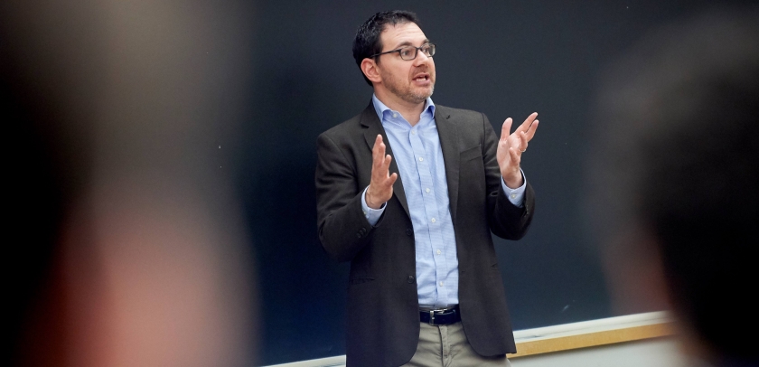 Dark haired man speaking and gesturing 