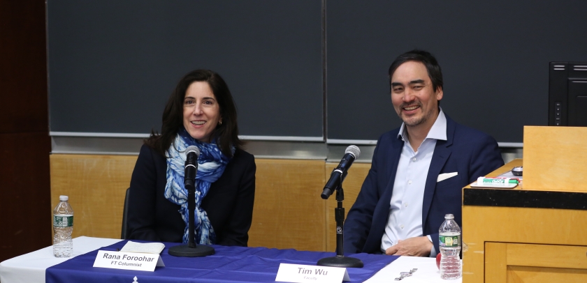 Woman and man sitting at panel table, smiling. 