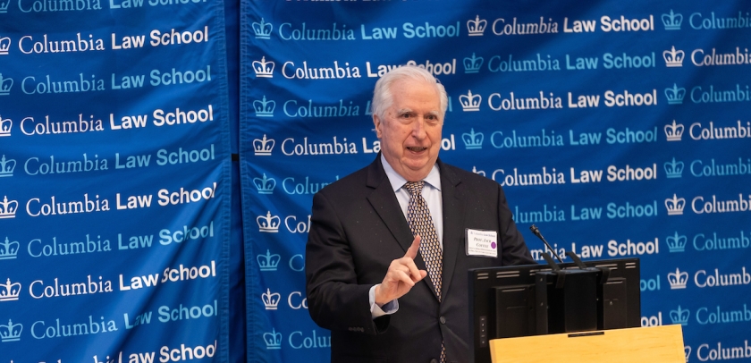 Man in tie at podium in front of Columbia Law School banner