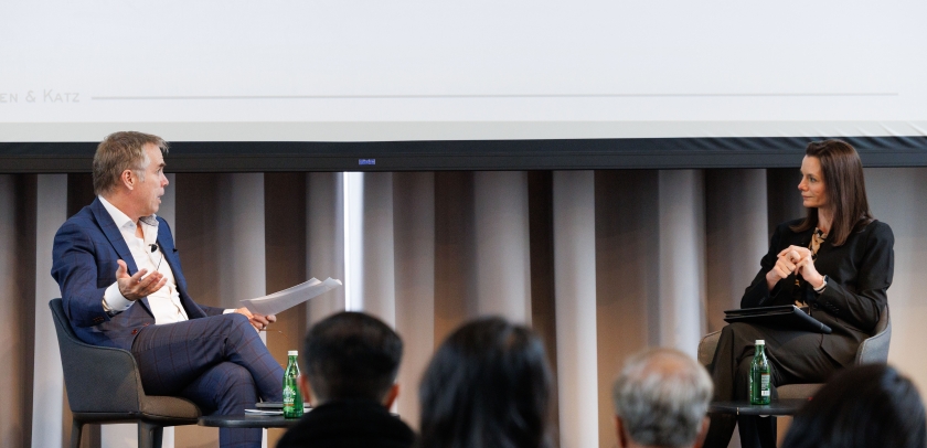 Man interviewing woman, both seated onstage
